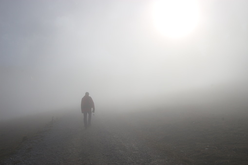 A man walks up a hill in dense fog. On a mountain footpath, height approx. 1300 m.  Hinterstoder, Upper Austria, Europe.