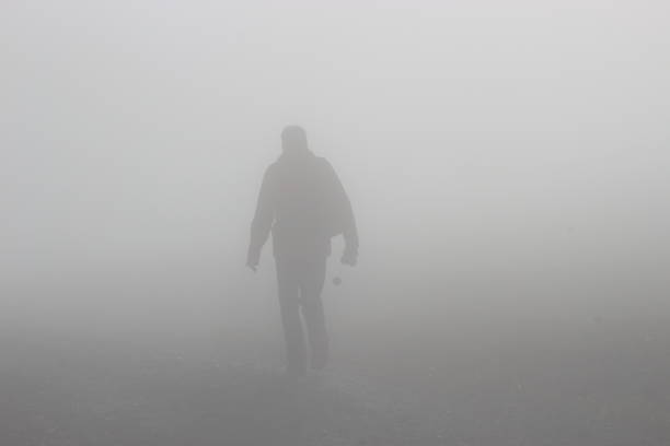 한 남자가 짙은 안개 속에서 언덕을 걷고 있다. 오스트리아. - invisible persons 뉴스 사진 이미지