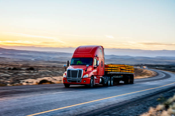 long haul semi trucks speeding down a four lane highway to delivery their loads - four lane highway stock-fotos und bilder