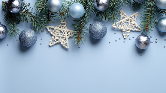 Christmas banner mockup. Christmas tree branches decorated blue and silver color balls, stars, confetti on pastel blue background. Xmas header design, greeting card template