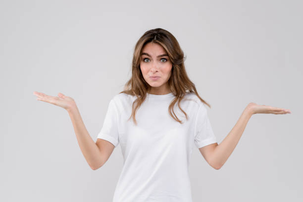 Beautiful young woman doubt expression, confuse and wonder concept, uncertain future shrugging shoulders, over white background