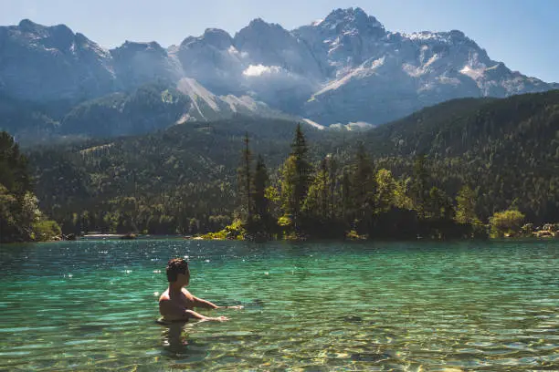 Man swimming in a beautiful mountain lake in the middle of the nature in the Bavarian Alps, Germany. European famous destination