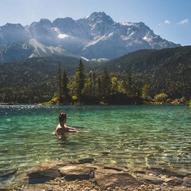 Man swimming in a beautiful mountain lake in the middle of the nature in the Bavarian Alps, Germany. European famous destination