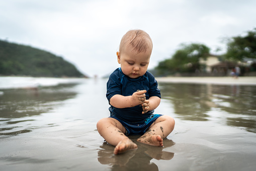 Cute baby playing in the sand at the beach