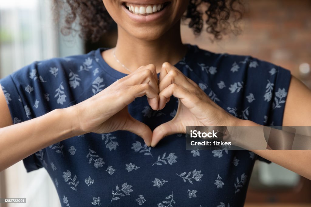 Smiling biracial woman show heart hand gesture Crop close up of happy African American woman feel grateful thankful show heart sign spread love and care. Smiling biracial female volunteer make hand gesture support ill sick people patients. Gratitude Stock Photo