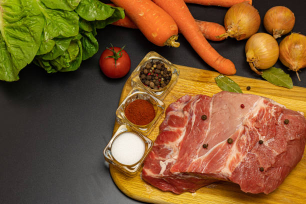 istock Piece of pork with fresh vegetables and spices on the table. 1282723643