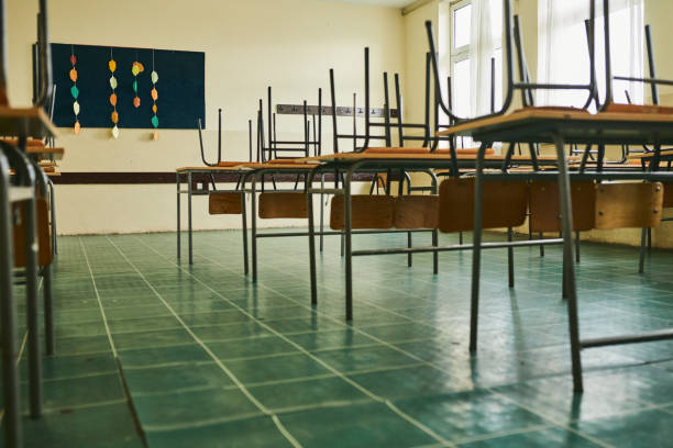 Empty classroom during COVID-19 pandemic Empty classroom with chairs on the table during COVID-19 pandemic empty desk in classroom stock pictures, royalty-free photos & images