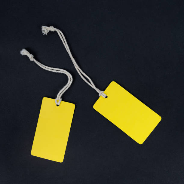 istock Two yellow fashion label tag mockup isolated on black. 1282725971