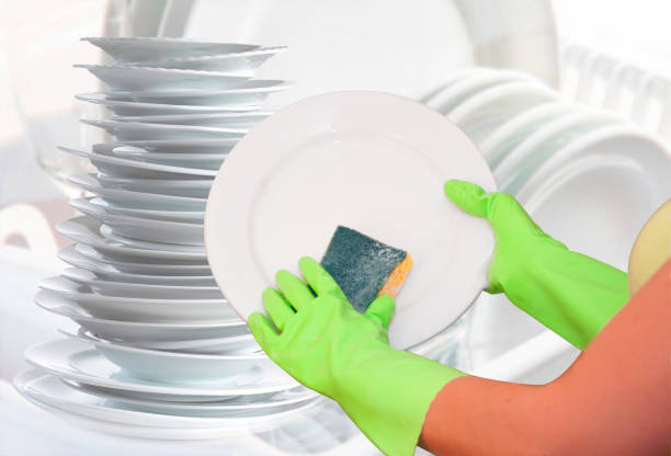 istock cleaning plates and kitchenware using sponge and green gloves. hands in pink gloves with yellow sponge 1282726964