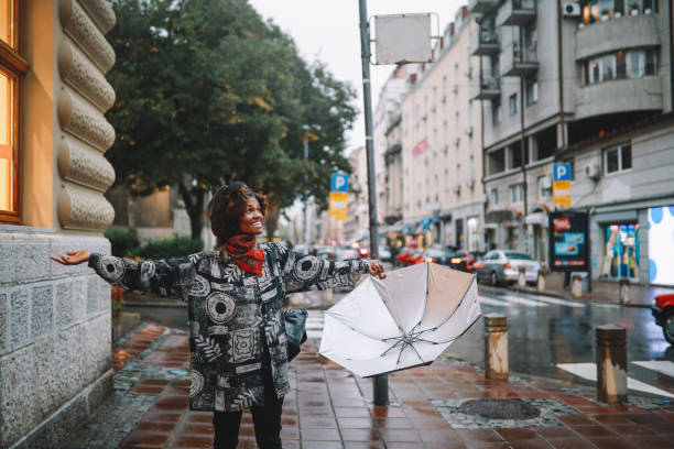 godersi una giornata piovosa - candid women african descent umbrella foto e immagini stock