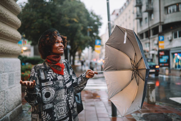 godersi una giornata piovosa - candid women african descent umbrella foto e immagini stock