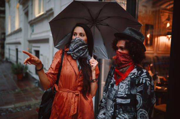 amici per strada che indossano bandane invece di maschere per il viso per uso interno - candid women african descent umbrella foto e immagini stock