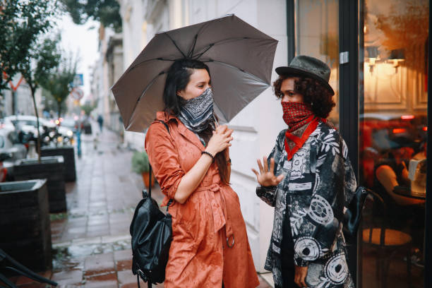amici per strada che indossano bandane invece di maschere per il viso per uso interno - candid women african descent umbrella foto e immagini stock