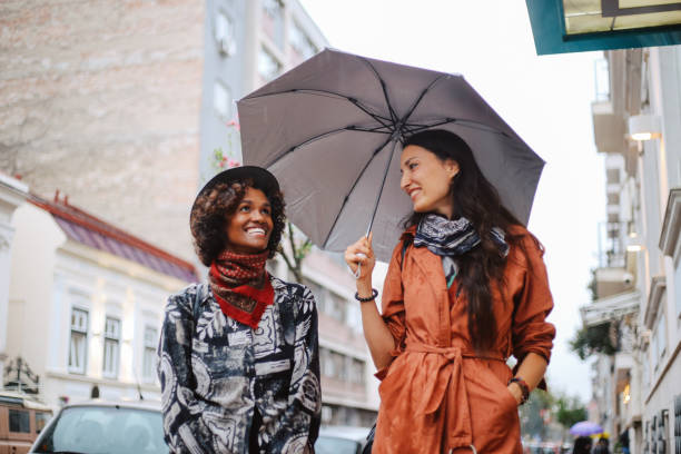 amici per strada che indossano bandane invece di maschere per il viso per uso interno - candid women african descent umbrella foto e immagini stock