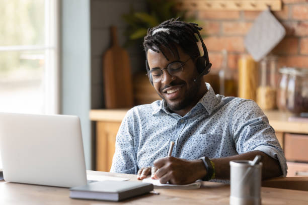 istock Smiling biracial man in headphones study online on computer 1282728190