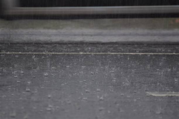 istock Rain on dark grey a asphalt road and some grass by the roadside 1282728512