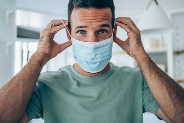 istock Young man putting protective medical face mask. 1282729497
