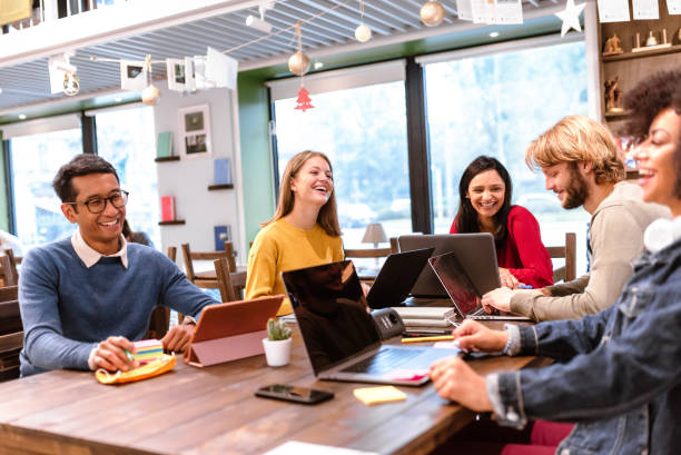 gruppo multietnico al lavoro, studenti in relax sorridenti, positivi e felici per i risultati ottenuti, concetto di cooperazione, brain storming, effetto orizzonte mosso per creare dinamismo - riunione del personale foto e immagini stock