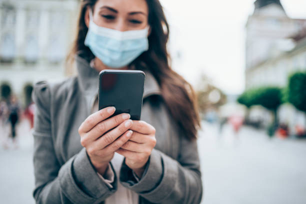istock Woman with protective face mask using smart phone outdoors. 1282729705
