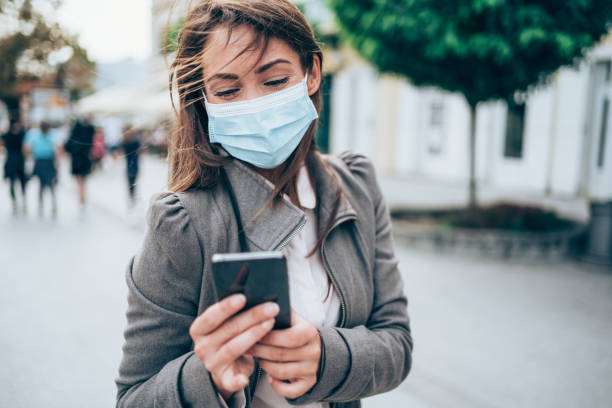istock Woman with protective face mask using smart phone outdoors. 1282729707
