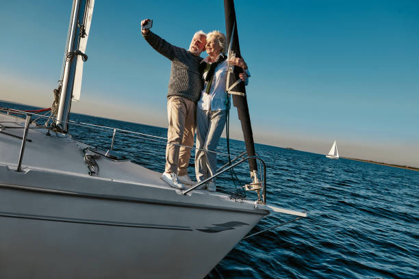 istock Capturing bright moments. Beautiful senior couple making selfie on smartphone while standing on the side of sailboat or yacht deck floating in sea 1282729758