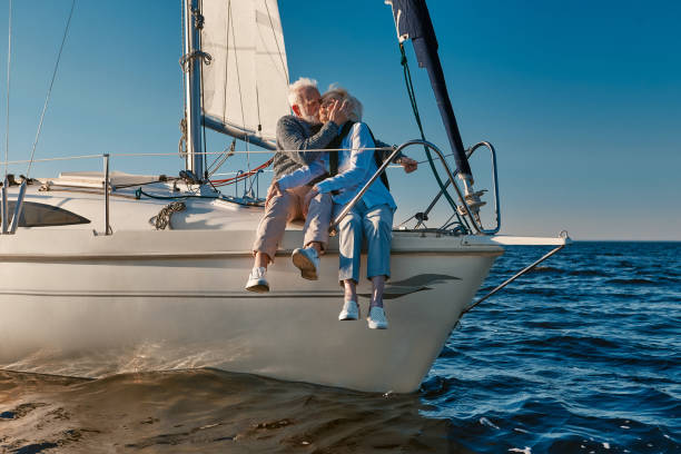 istock Romantic elderly couple embracing and kissing while relaxing on sail boat or yacht deck floating in a calm blue sea at sunset 1282729842