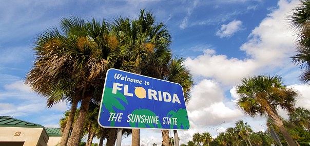In Yulee, United States a welcome to Florida state sign is visible with palm trees at a highway rest stop south of the Georgia border.