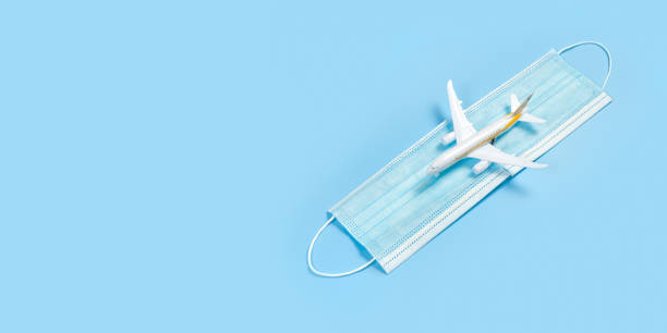 istock Plane model and face mask on a blue background. Flight impact of coronavirus (COVID-19) concept. 1282732262