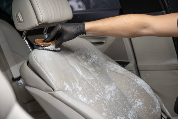 istock Car detailing studio worker cleaning car interior and car leather seats with a brush. 1282732404
