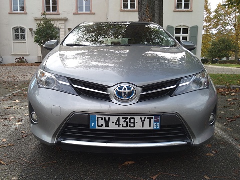 Toyota Auris hybrid, metallic gray 5-door sedan car, city of Irigny, Rhône department, France
