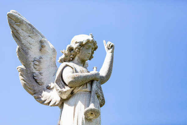istock Angel, old statue of angle with trumpet, light blue sky background with copy space 1282734186