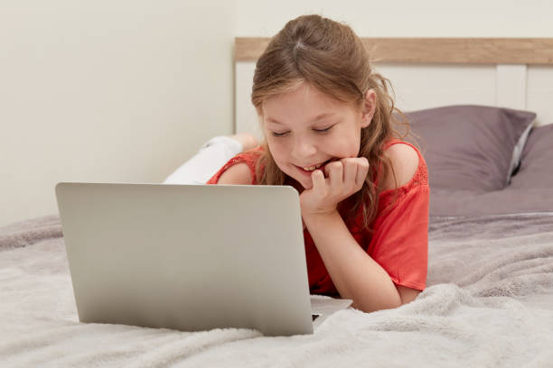 istock Beautiful smiling girl studying online from laptops, lying in bed. 1282734506