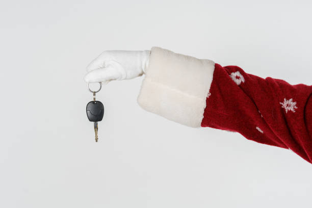 istock Santa Claus is holding a gift - car keys. Isolated on light background 1282735821