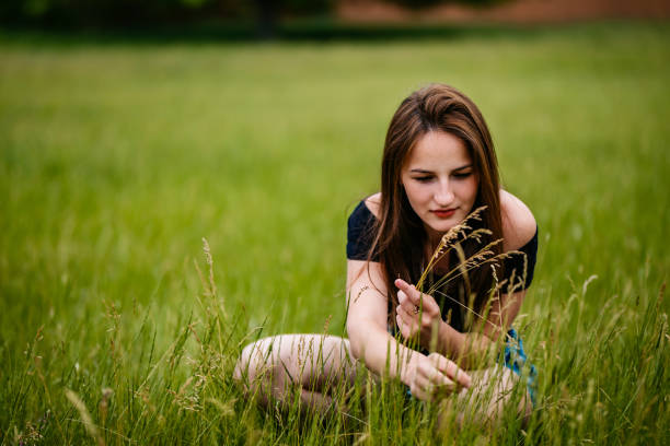 Portrait of pretty young Caucasian woman crouching in grass.