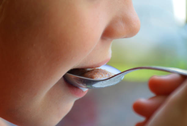 istock woman eating with a spoon close up 1282738797