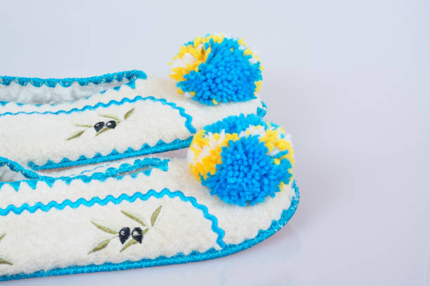 Pair of woolen slippers with blue pumpons on gray background