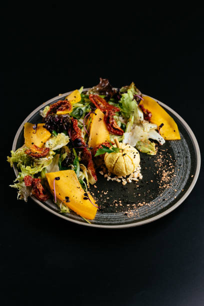 istock autumn salad with pumpkin and sun-dried tomatoes on a black back 1282750610