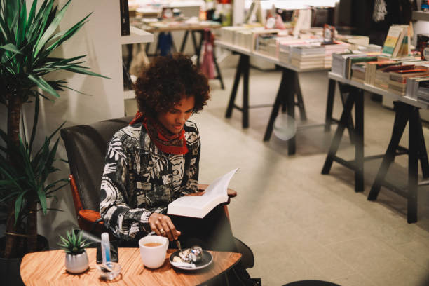 istock Young black woman reading in a bookstore cafe 1282750678