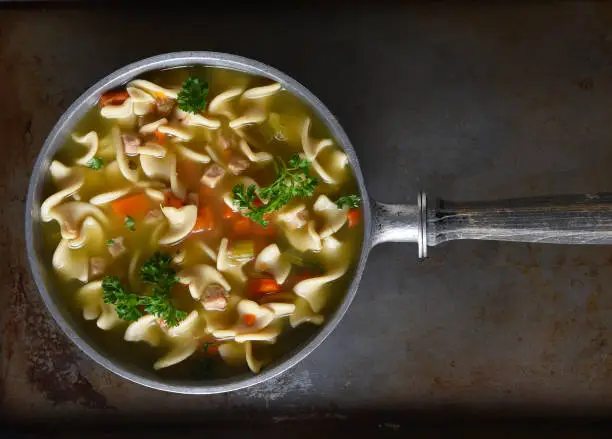 Top view of a pot of fresh homemade, Chicken Noodle Soup. Horizontal format with copy space. Can be rotated - works as a vertical as well.