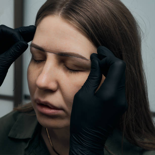 istock Permanent eyebrow makeup procedure. Eyebrow tattooing, process. The use of tools by a master for permanent eyebrow makeup. 1282756817