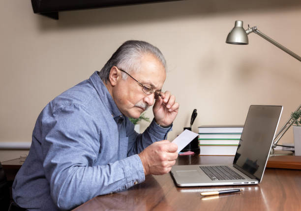 istock Senior man learn to use computer. Old man in glass and blue shirt Reads instructions for work using a laptop computer for online studying at home office 1282758478
