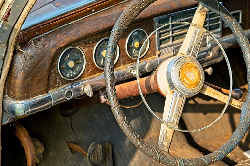 Interior of a old rusty car, with a 3 speed on the column.