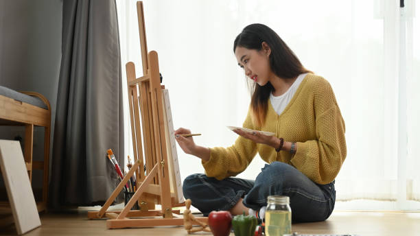 istock A young female artist painting on easel while enjoying work in art studio. 1282775677