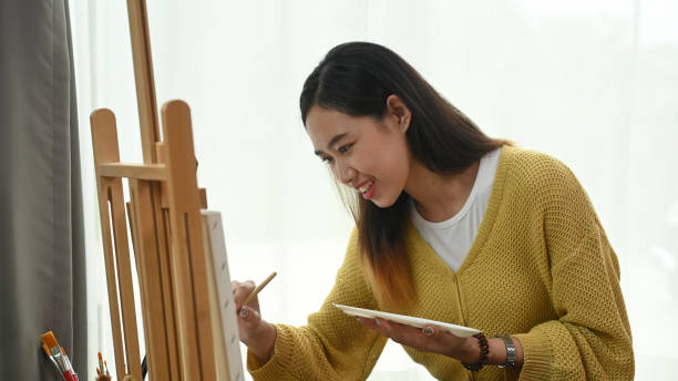 istock A pretty talented female painter is painting on easel at her workshop. 1282775739