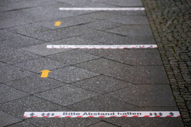 istock Stickers on the pavement outside a shop read 'Please keep distance' 1282775906
