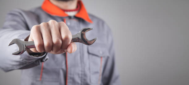 istock Man wearing a uniform holding a wrench. 1282786003