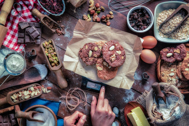 mani di giovani donne che posizionano biscotti al cioccolato e noci sulla bilancia digitale. - biscotti cookie chocolate pistachio foto e immagini stock