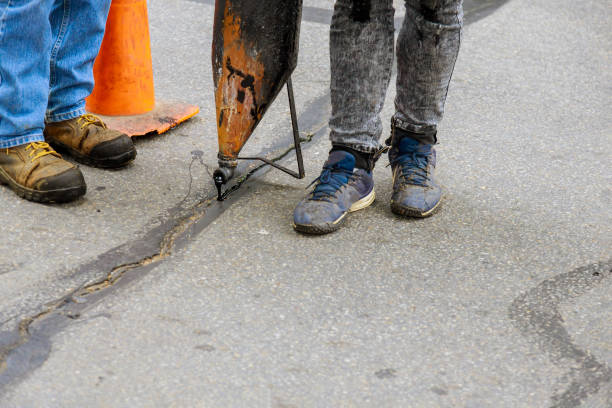 istock Workers perform minor repairs to pavement by spraying liquid asphalt into pits on roadway sealing cracks 1282788645