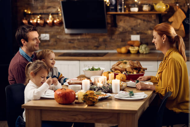 istock Happy family enjoying in Thanksgiving dinner at dining table. 1282792274