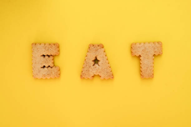 istock Cookie alphabet symbols E A T on top view with yellow background 1282793481